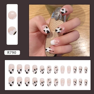 Macro detail of French almond press-on nails featuring cow print and white drip designs