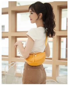 Detailed view of yellow crocodile embossed saddle bag worn by model in a warm setting