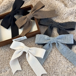 Knitted bow hair clip set in earthy tones showing ribbed texture on soft plush background