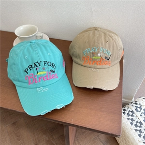 Vintage cotton baseball caps in mint green and khaki with golf embroidery on wooden desk