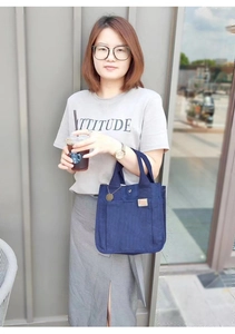 Detailansicht einer dunkelblauen Canvas-Tasche mit Vordertasche, präsentiert vom Modell