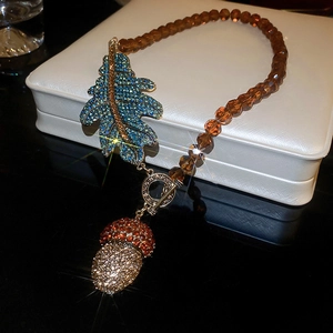 Gros plan du collier pendentif gland vintage avec feuille de cristal bleu et boîte