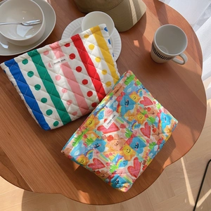 Quilted cotton cosmetic bag with floral patterns and stripes on a rustic wooden table