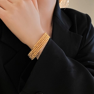 Detail of four-layer gold plated beaded bracelet with textured surface on model