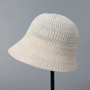 Close-up of the breathable hollow knit texture on a beige sun hat with crochet pattern