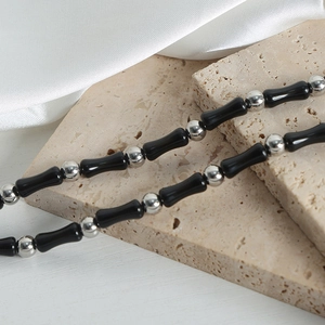 Handmade black agate and silver bead necklace on beige stone and white satin