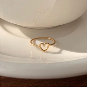 Detailed close-up of a gold hollow heart ring placed on white ceramic tableware edge