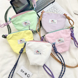 Flat lay of colorful canvas phone bags with rainbow braided straps on white fabric