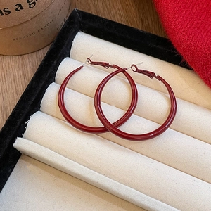 Detail of red circular hoop earrings on a velvet jewelry tray with a candle background