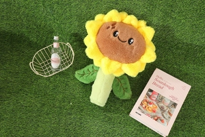 Gros plan d'une peluche tournesol avec un visage souriant sur fond d'herbe verte