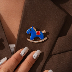 Detail of blue enamel rocking horse brooch with rhinestones on a brown blazer lapel