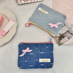 Detail view of denim coin purses with embroidered bows and pastel ribbon accents