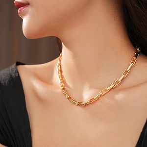 Close-up of a minimalist gold link chain necklace worn on a model's neck