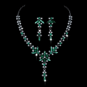 Detailed view of necklace set with sparkling green gems and clear crystals on black background