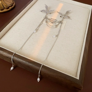 Detail of silver phoenix earrings with long tassels and teardrop pearls in a jewelry box