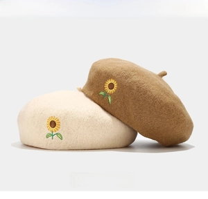 Detailed close-up of wool beret with sunflower embroidery in cream and brown tones