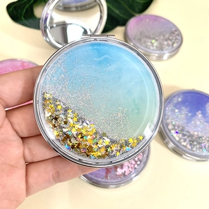 Macro detail of foldable glitter compact mirror with teal gradient and star sequins