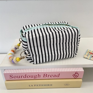 Detail of fabric tissue bag with black stripes and colorful beaded chain handle