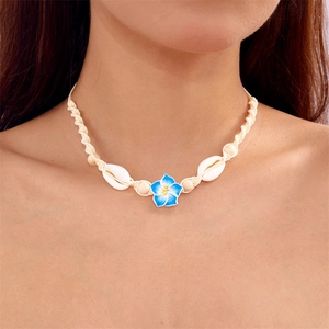 Detail of woven neckband with white seashell and blue floral pendant on model's neck