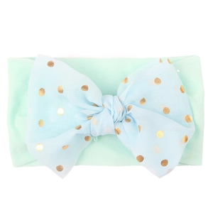 Detail of light green nylon headband with a large blue tulle bow and gold polka dots