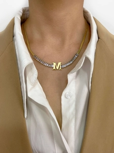 Detail of gold letter M pendant with baguette-cut crystals on a sleek snake chain