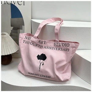 Detail of pink canvas tote bag with black floral print on white geometric stand