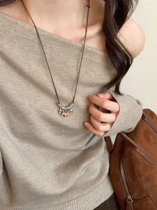 Detail of wooden horse pendant with matte silver rings on a long woven necklace cord