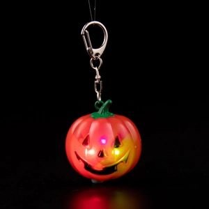 Close-up of glowing Halloween pumpkin keychain with colorful LED light and silver ring