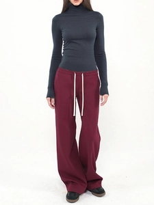 Detail of grey wool knit turtleneck top with deep red drawstring wide-leg pants