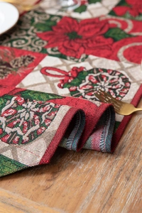 Detail of jacquard woven Christmas table runner with festive floral and pinecone patterns