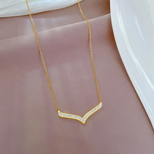 Macro shot of gold V-shaped pendant necklace with tiny zircon crystals on brown silk