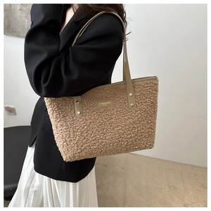 Detail of plush khaki tote bag featuring brand logo patch and soft texture for winter