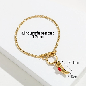 Detail of golden Figaro chain bracelet with red stone horn charm and OT toggle clasp