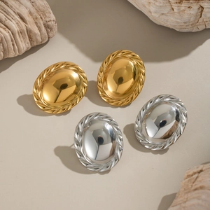 Macro detail of oval gold and silver mirror earrings with spiral textured edge