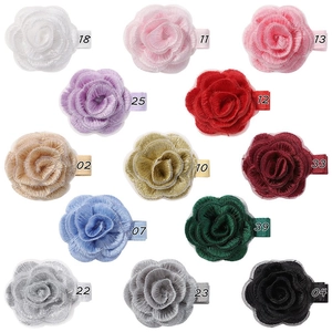 Flat lay of thirteen colorful handmade fabric rose hair clips on a clean white background