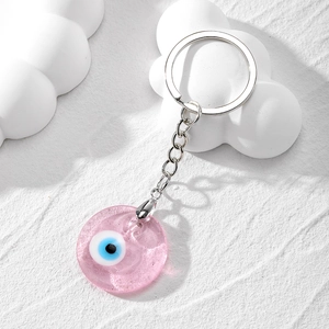 Close-up of pink resin Evil Eye pendant keychain on a minimalist white texture base