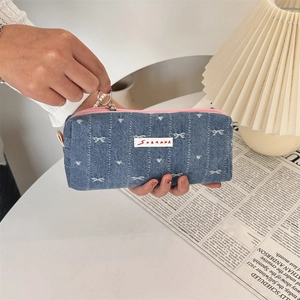 Close-up of denim fabric pencil case with white bow embroidery and pearl handle loop