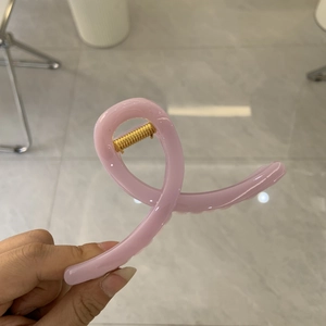 Minimalistische Haarspange in Rosa mit überkreuztem Design und goldener Feder