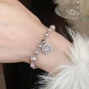 Detail of elegant pearl bracelet with a sparkling zircon pendant on model wrist