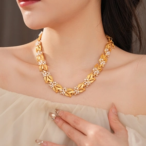 Macro detail of vintage gold necklace with white pearl and zircon leaf pendant on model