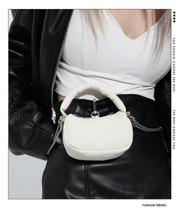 Close-up of white semi-circular mini handbag with textured fabric and silver zipper