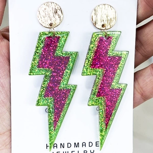 Neon lightning bolt earrings with pink and green glitter acrylic layers on white card