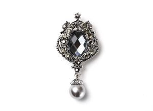 Detailed macro view of baroque silver cross brooch with grey gemstone and pearl pendant