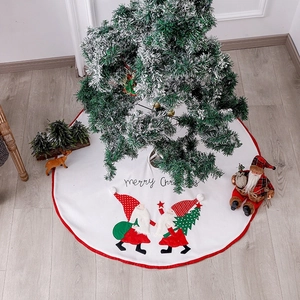 White Christmas tree skirt with red border and festive gnome embroidery on wood floor