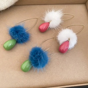 Dettaglio di orecchini a goccia con pompon invernali in colori blu e bianco a contrasto