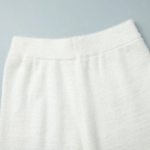 Detail of soft white knit fabric showing thick elastic waistband and plush texture
