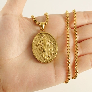 Detailed view of oval 18k gold Jesus relief pendant with box chain on palm