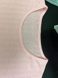 Detail of pink crew neck rib-knit top featuring delicate pointelle cutout patterns