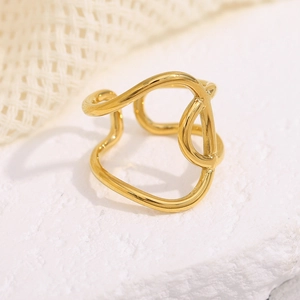 Detailed view of an 18K gold-plated knotted cross ring on a textured stone surface