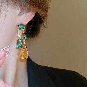 Détail de boucles d'oreilles pendantes avec zircons verts et jaunes plaqués or